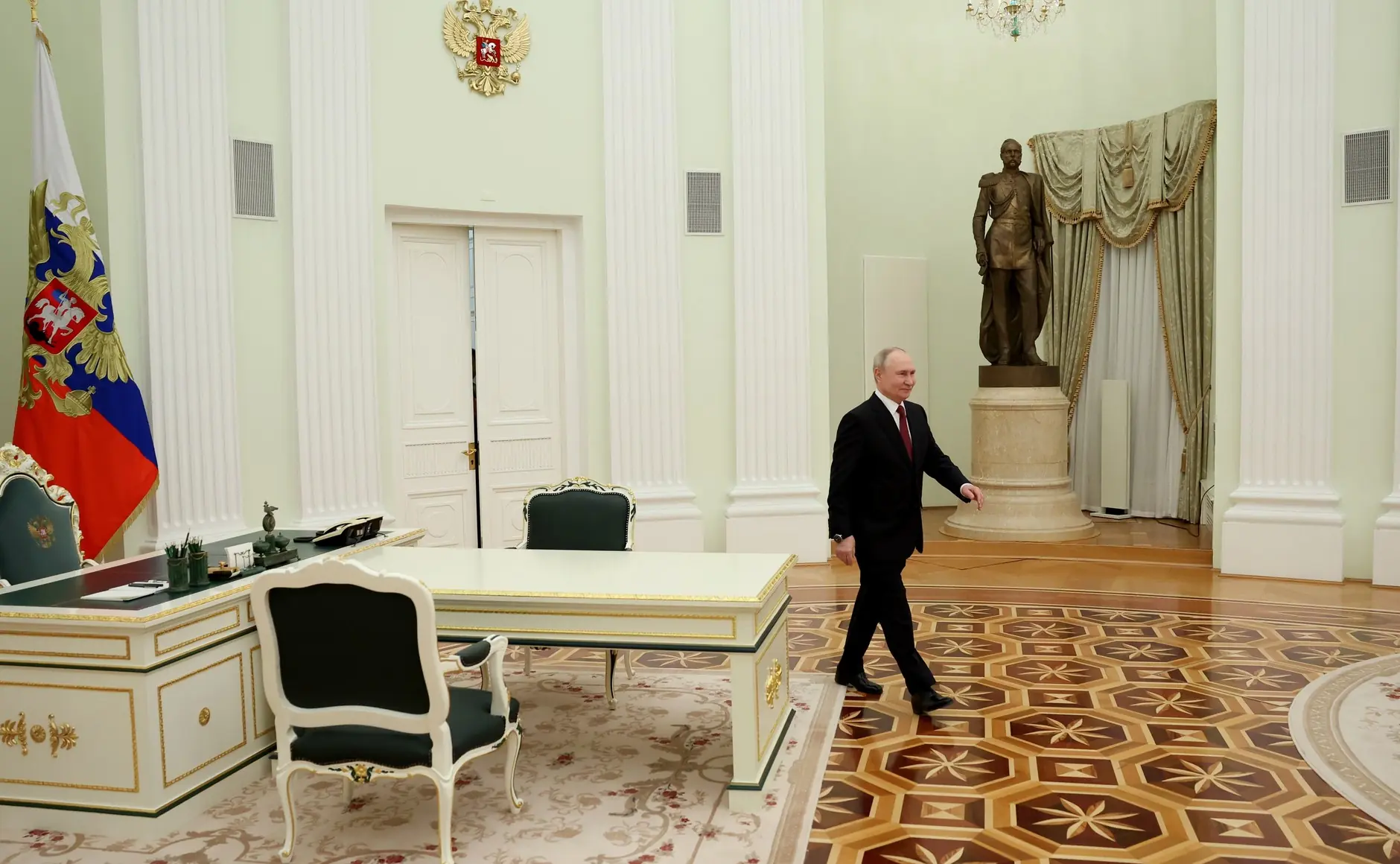 Le président russe Vladimir Poutine lors d'une réunion au Kremlin, en costume sombre.